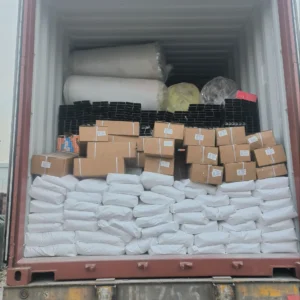 Open shipping container fully loaded with white bags, cardboard boxes, and rolled materials, organized neatly for transport.