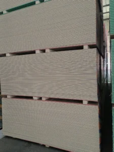 Large stacks of drywall panels stored in a warehouse, showing organized rows and industrial shelving.