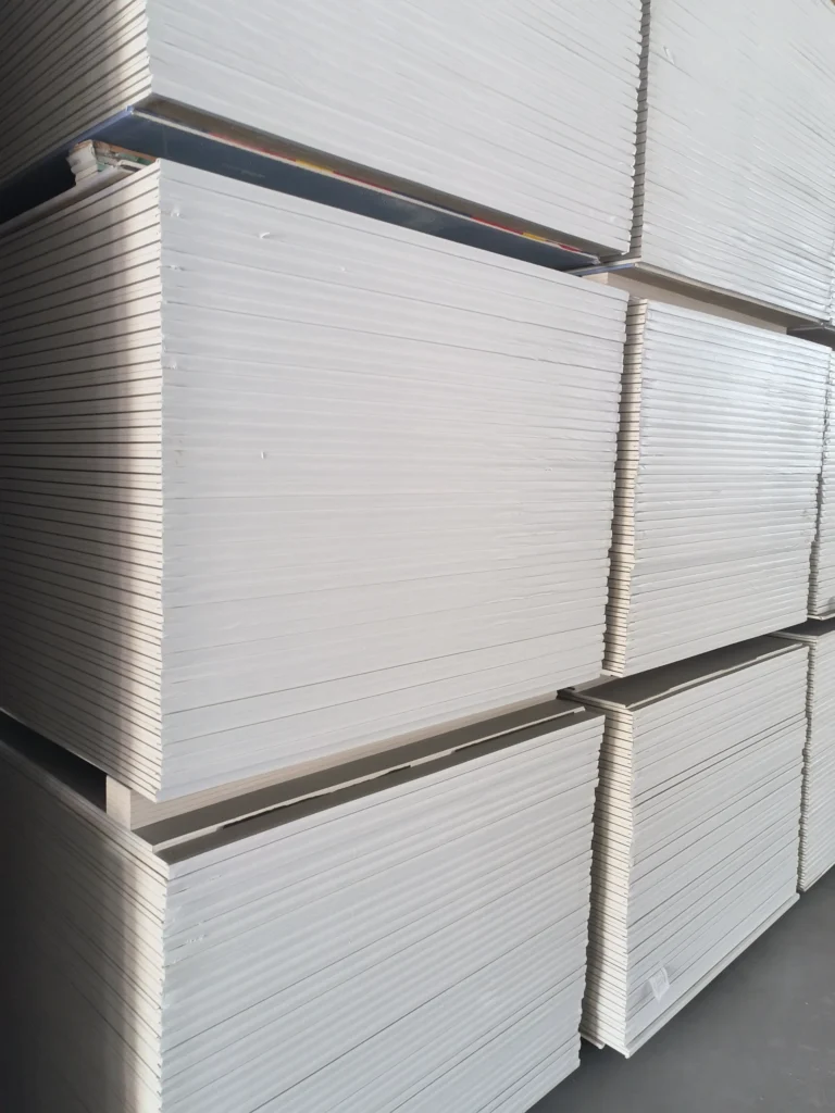 Large stacks of white drywall sheets neatly arranged in a warehouse setting.