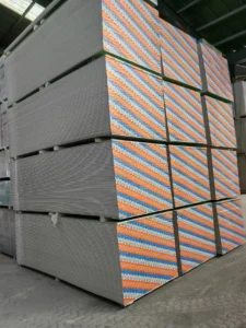 Large stacks of fiber cement boards with striped edges, organized in a warehouse setting.