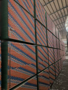 Large stacks of gypboard panels labeled 'TRUSUS' arranged in a warehouse with a high ceiling, showing organized industrial storage.