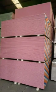 Large stacks of pink drywall sheets organized in a warehouse setting.