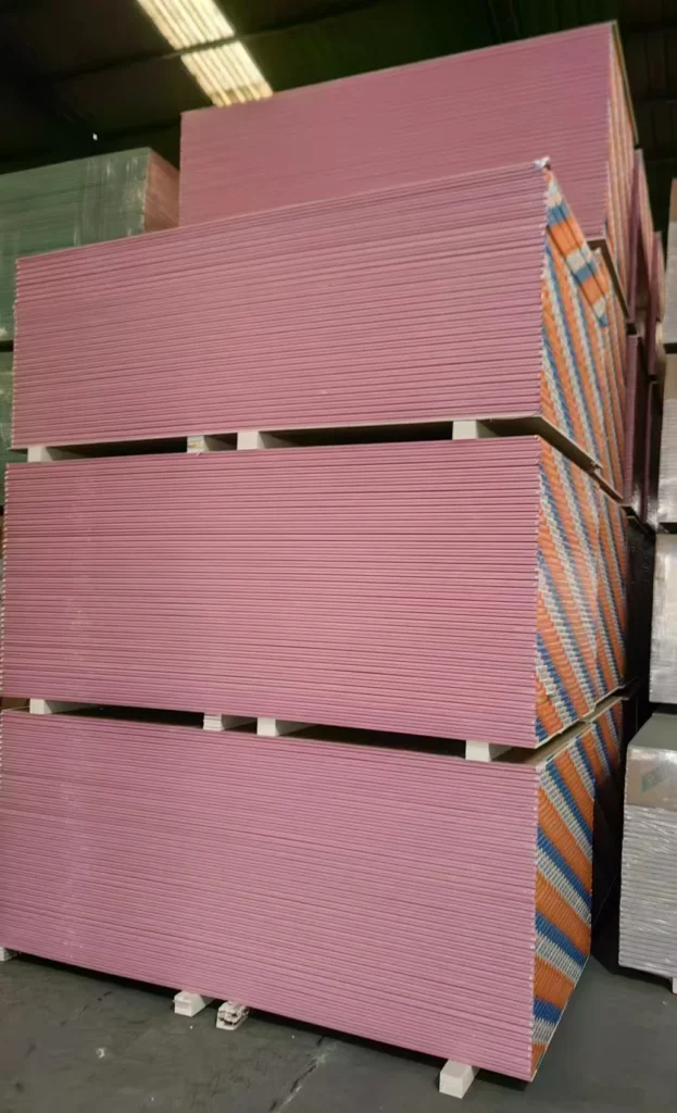 Large stacks of pink drywall sheets organized in a warehouse setting.