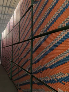 Large stacks of gypsum board with 'Trusus' branding in a warehouse, arranged neatly under a high ceiling.