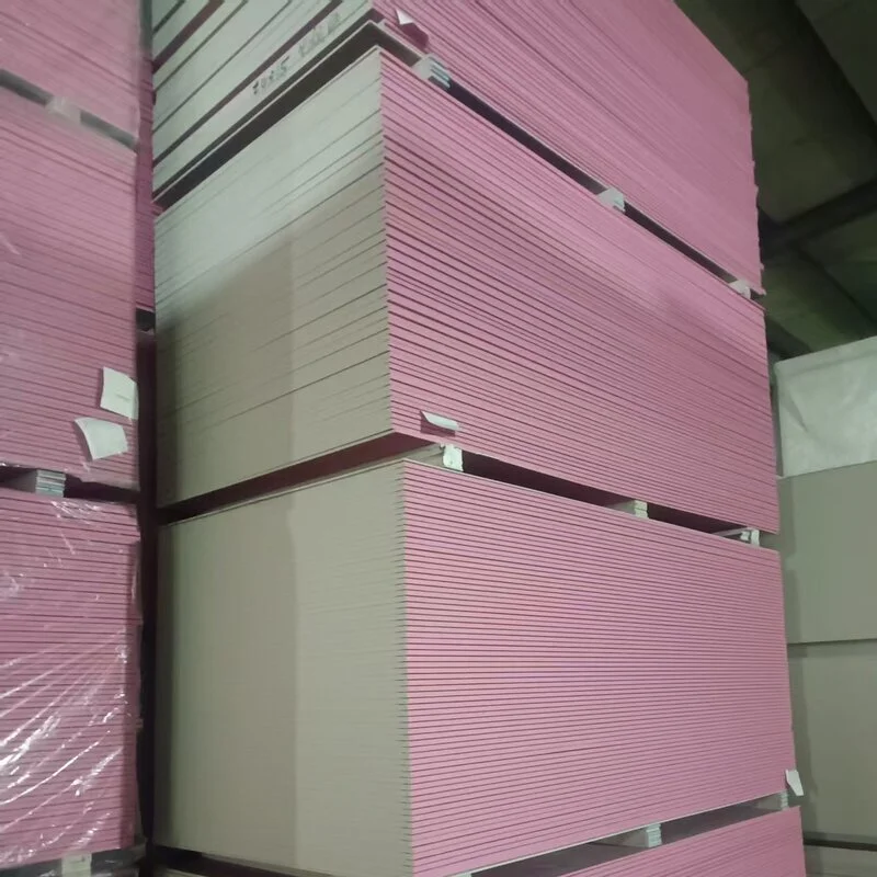 Large stacks of pink drywall sheets neatly piled in a warehouse setting.