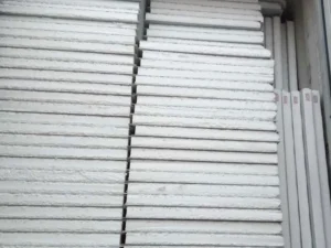 Neatly stacked white gypsum boards, visible texture and thickness, organized in a warehouse setting.