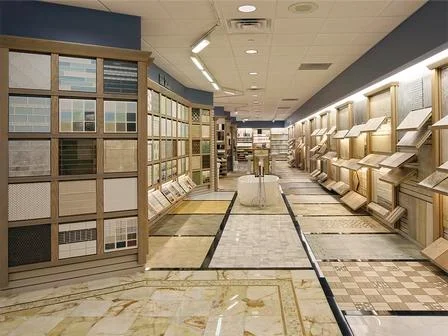 Interior of a tile showroom featuring a wide variety of floor tiles on display, with different designs and patterns along the walls and floor.
