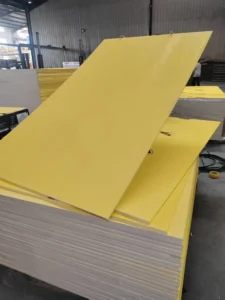 Stack of large yellow panels in a factory setting, positioned over white panels with a visible warehouse background.