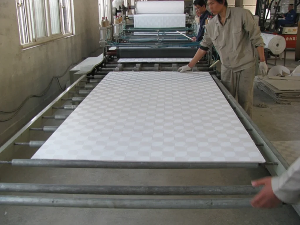 Two workers monitoring a fabric production line with patterned fabric in a factory setting.